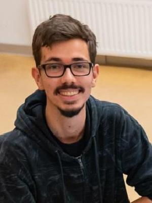 Roman Sillipp, junger Mann mit Brille in dunklem Hoodie, lächelnd