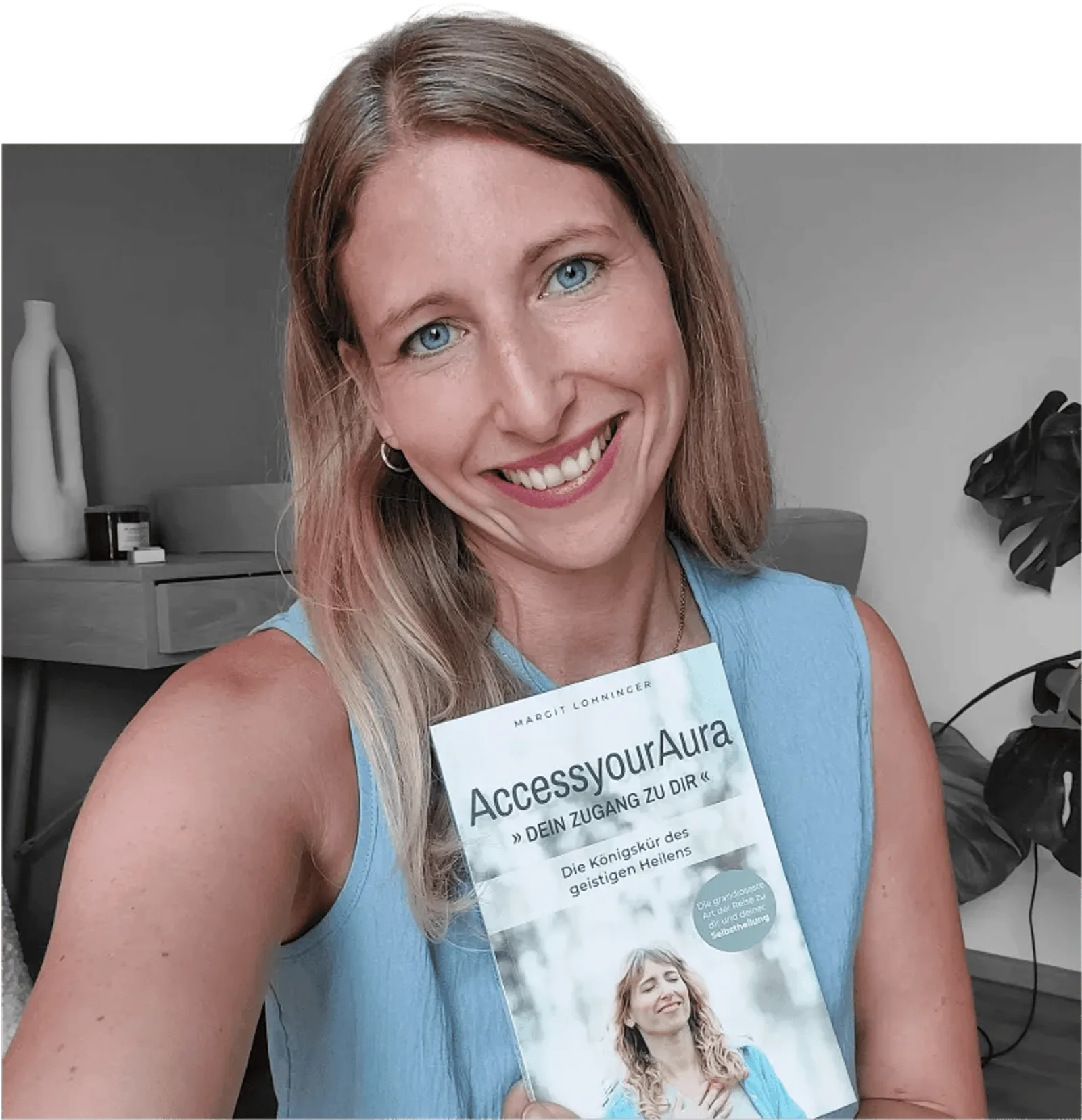 Porträt Margit Lohninger mit Buch AccessyourAura in blauem Top