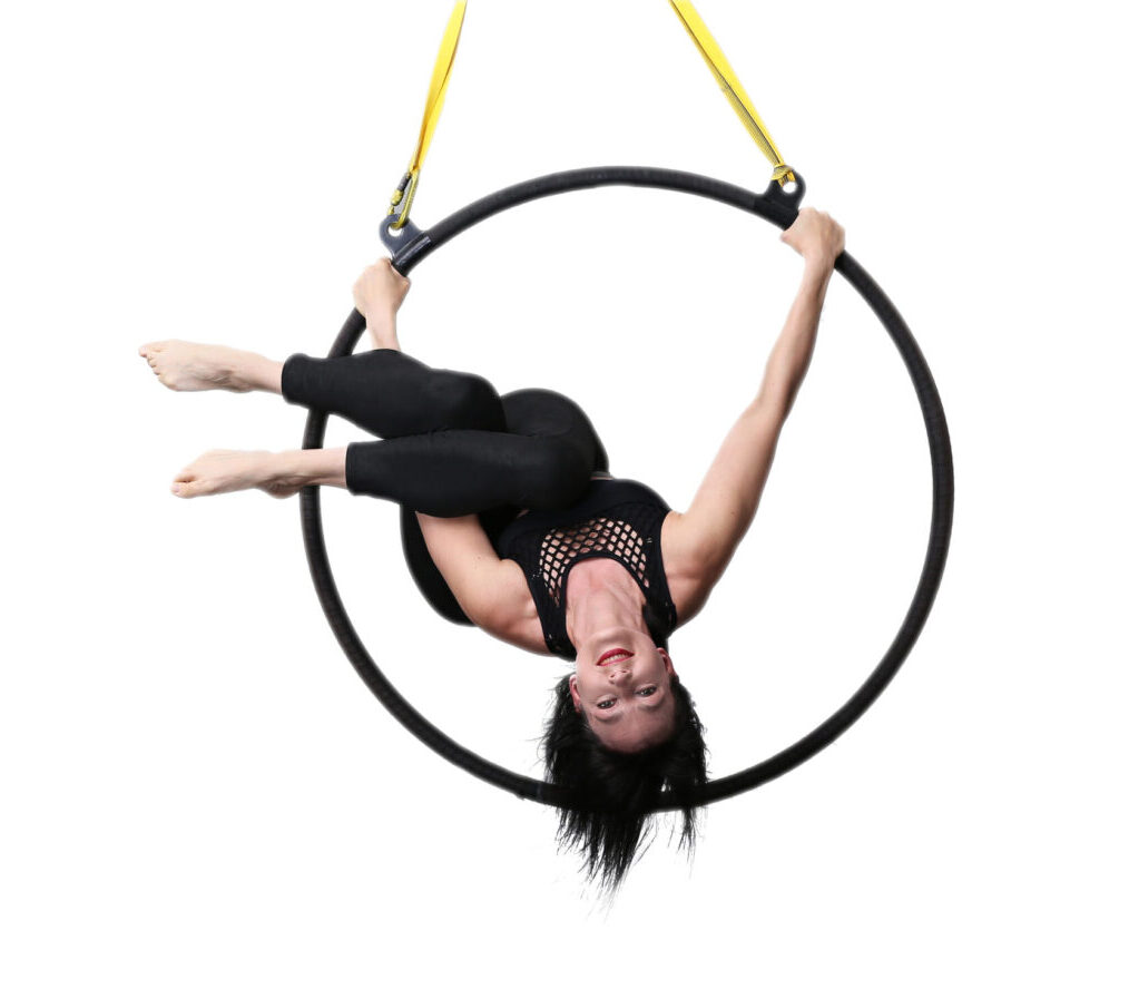 Aerial Hoop Performer kopfüber in schwarzem Outfit mit gelbem Aufhängungsseil