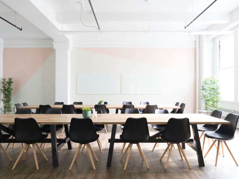 Moderner Seminarraum mit langer Holztafel, schwarzen Stühlen und Whiteboard