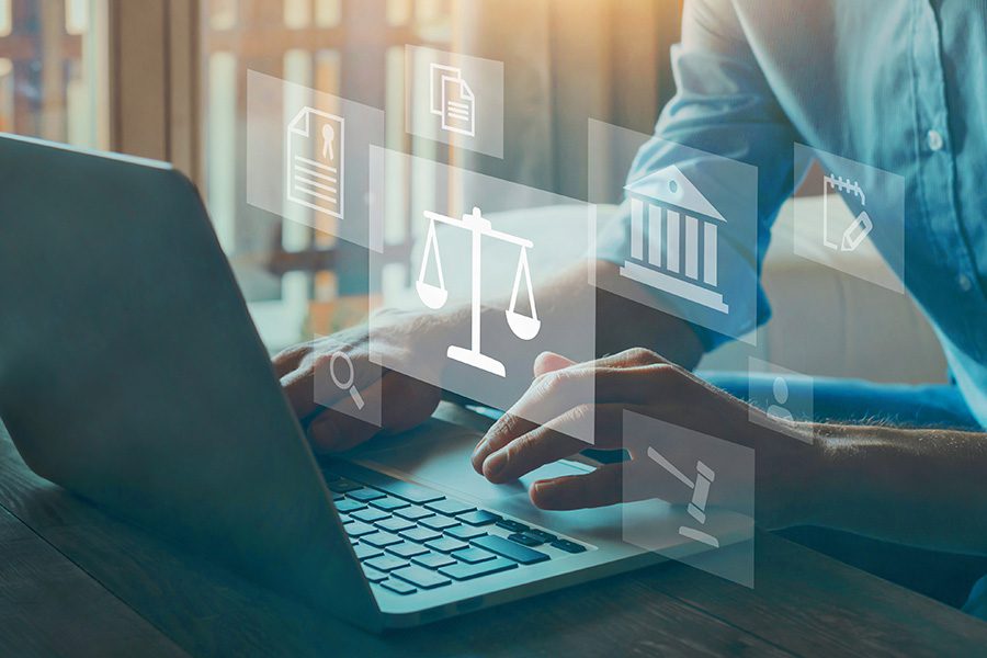 Justizia-Waage und Gesetzbuch-Icons auf Laptop-Bildschirm, Geschäftsfrau-Hände über Tastatur