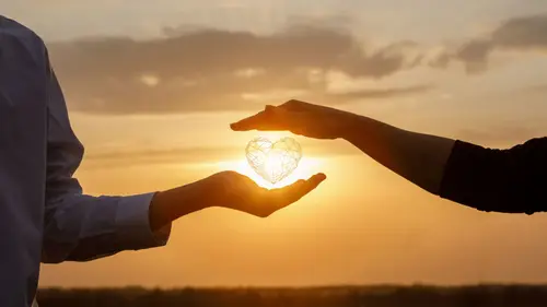 Zwei Hände halten eine leuchtende Kugel im Sonnenuntergang, symbolisiert Verbundenheit und Beziehungsaufbau