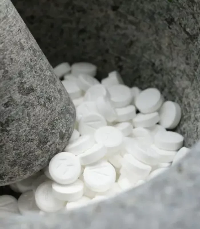 Schüsslersalz-Tabletten zwischen Steinen in Mörser, Produktfoto