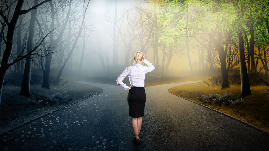 Frau in Business-Kleidung an Weggabelung im Wald, symbolisiert Entscheidungsfindung und Orientierung