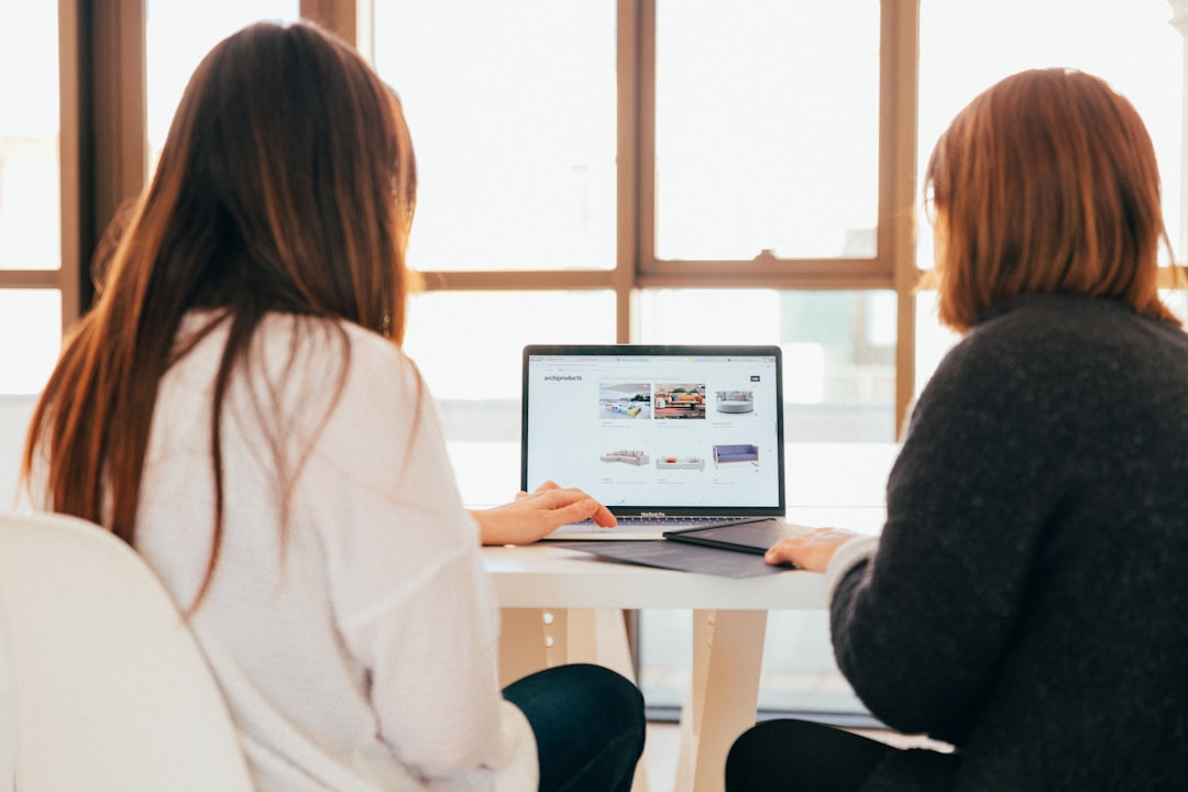 Zwei Personen betrachten Website-Design auf Laptop