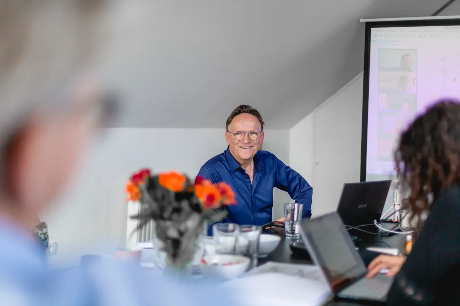 Ernst Albrecht Vöhringer sitzt lächelnd mit Teilnehmern am Tisch