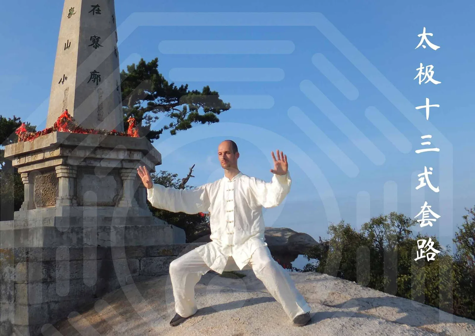 Tobias Puntke in weißer Kampfkunst-Kleidung in Taiji-Pose vor chinesischem Denkmal mit blauem Himmel