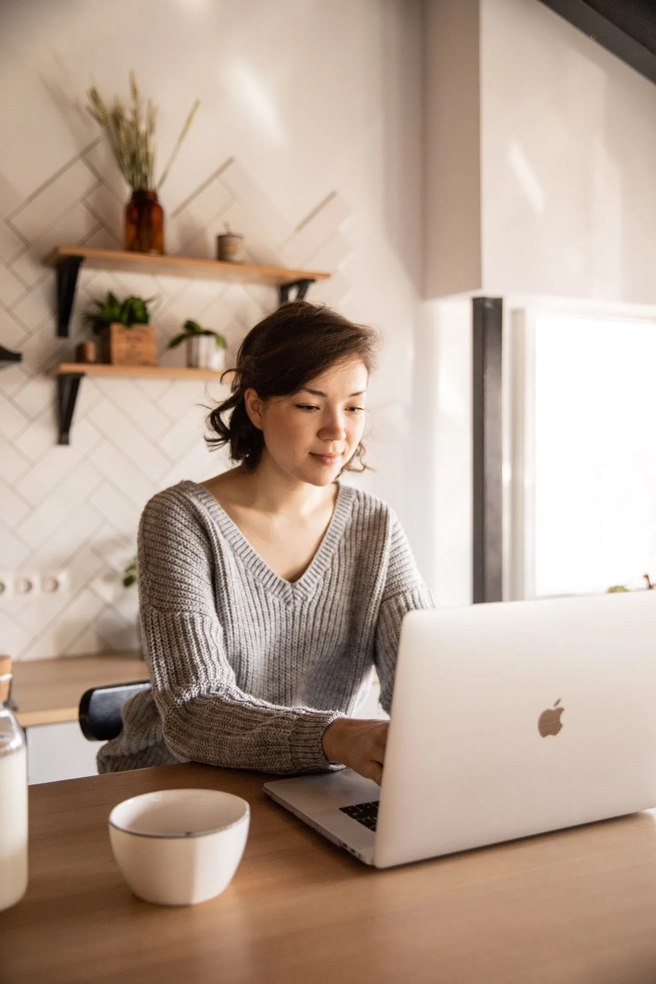 AURIN – Videokurs zur Bibel für Christentum & Bibel 6 Frau arbeitet am Laptop im minimalistischen Home-Office mit Regalen und Pflanze