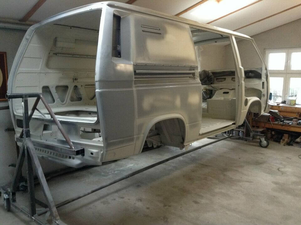 Weiße VW Transporter Karosserie auf Auto Drehgestell in beleuchteter Werkstatt