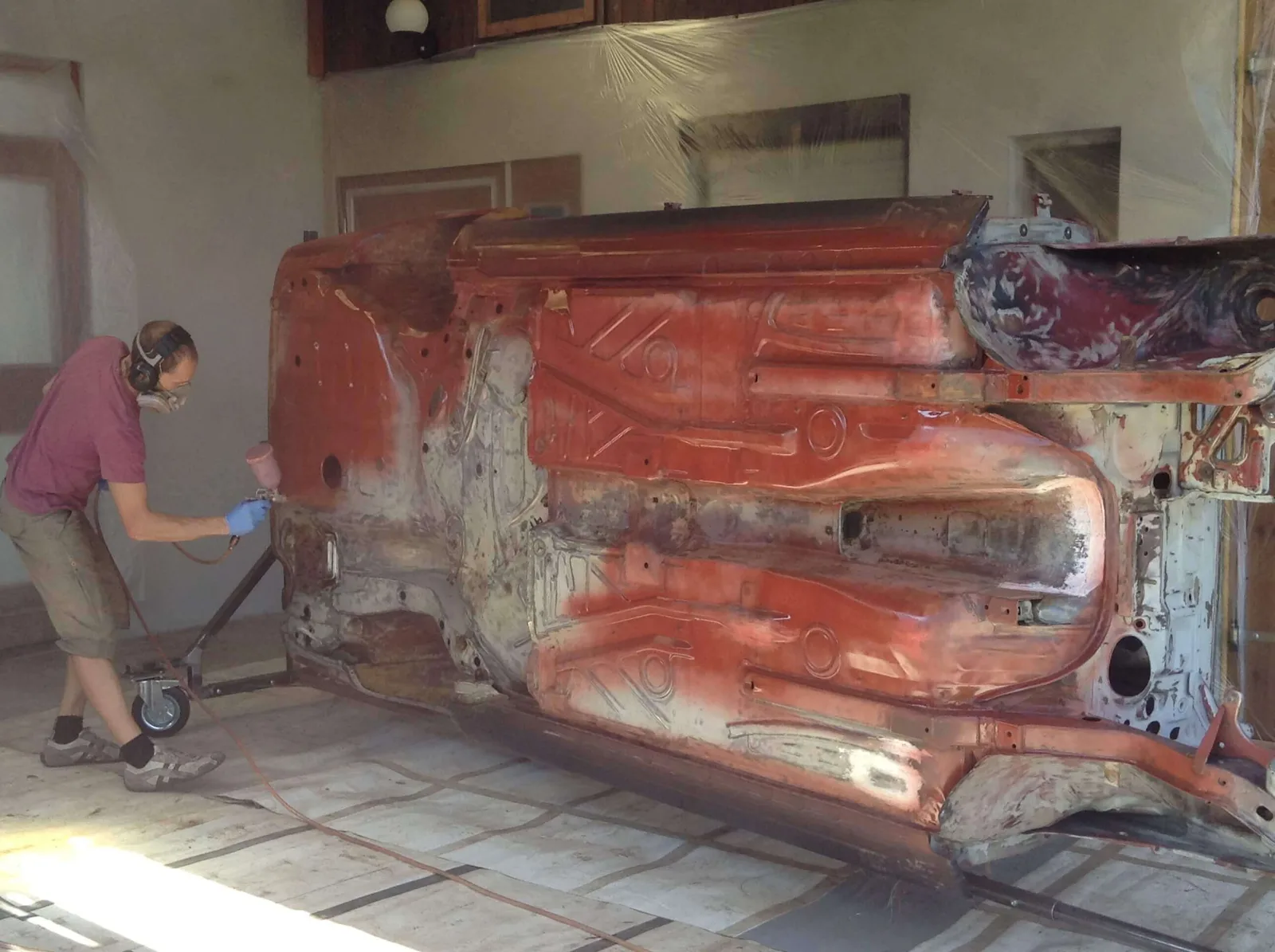 Arbeiter bearbeitet Karosserie mit Schleifergerät auf Auto Drehgestell