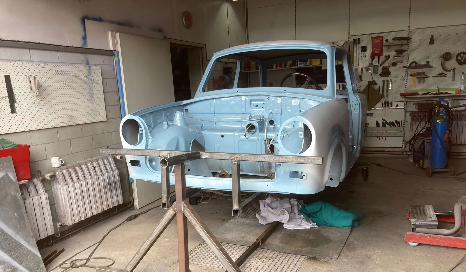 Hellblauer Trabant auf Auto Drehgestell in Werkstatt, Motorraum offen