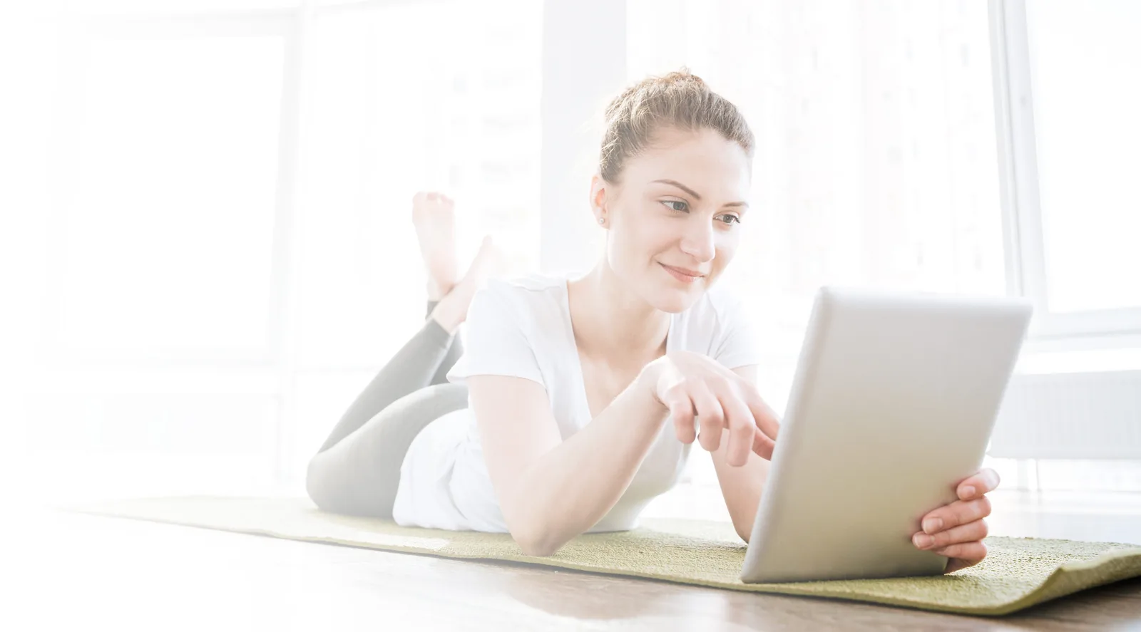 Frau mit Tablet am Boden liegend, modernes Zimmer, Online-Kurs