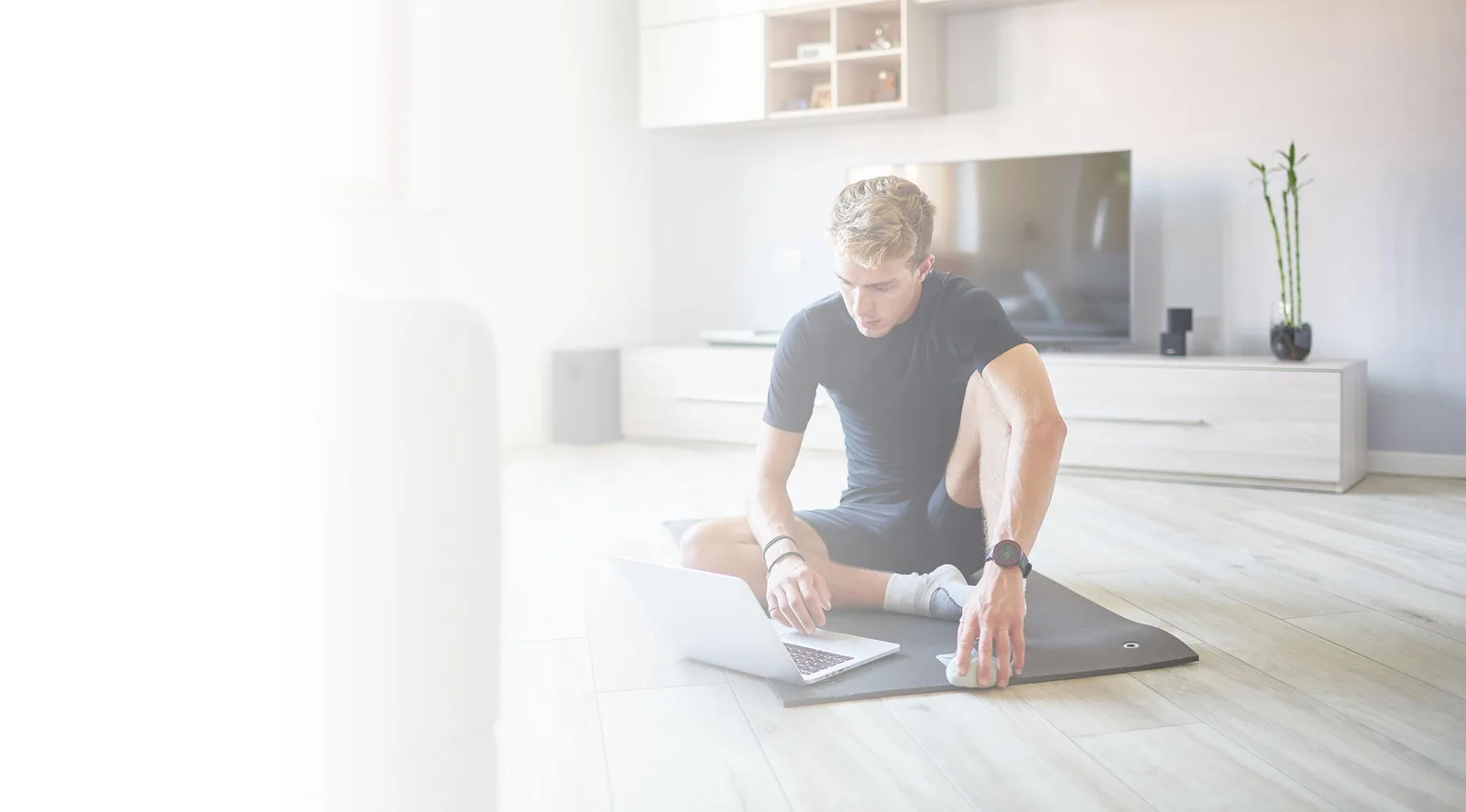 Mann auf Yoga-Matte mit Laptop, Home-Fitness-Training