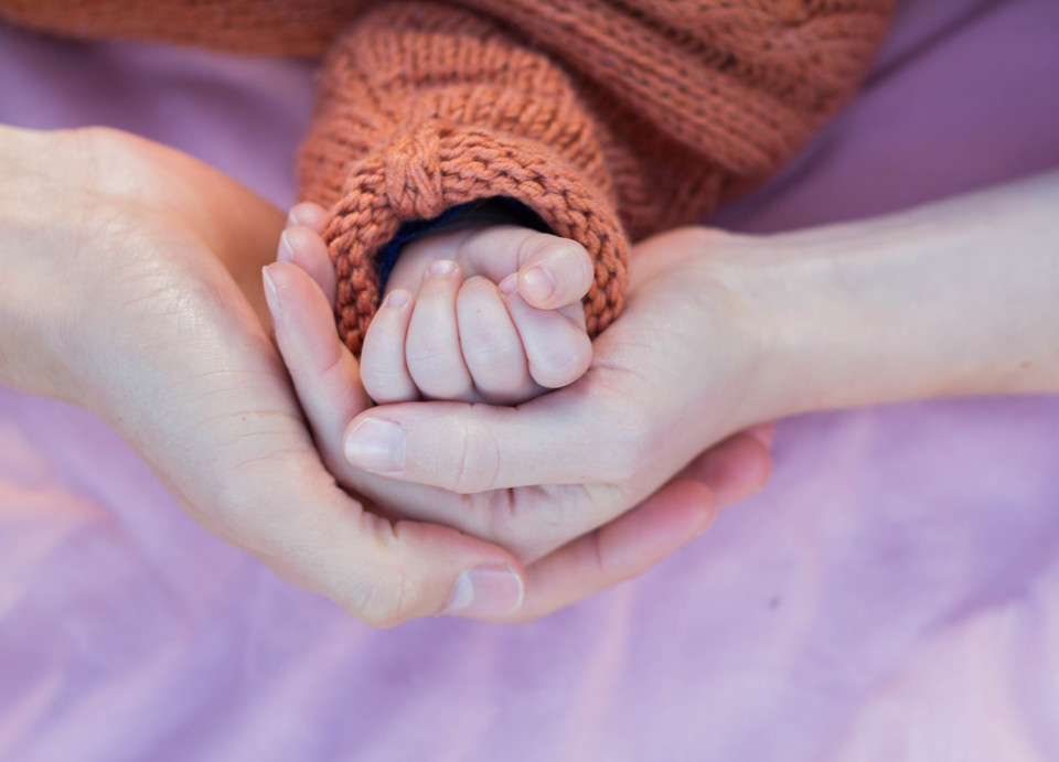 Babyhandling – Videokurs für Eltern von Pelle Wiedling 8 Babyhände halten Erwachsenenfinger – Nahaufnahme auf violettem Hintergrund