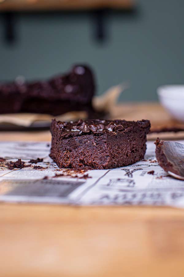 Einzelner Brownie auf Papier mit Löffel, unscharfer Hintergrund, Nahaufnahme