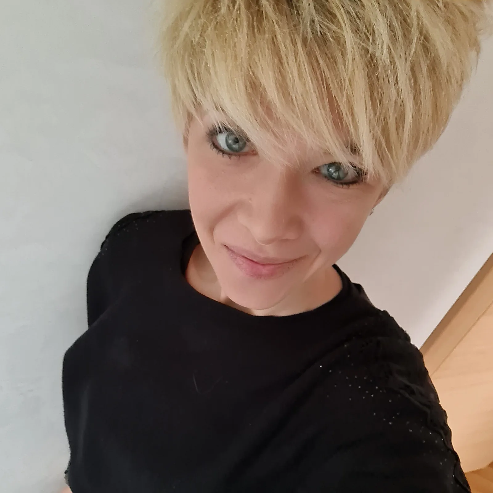 Porträt einer blonden Frau (Steffi) mit kurzer Frisur in schwarzem Shirt vor hellem Hintergrund