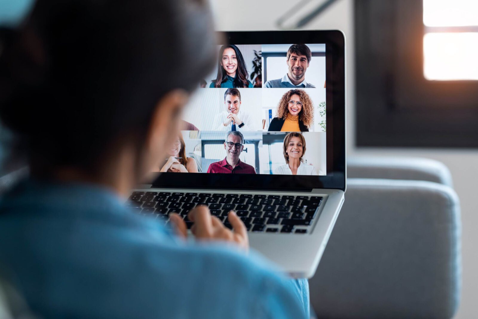 Videokonferenz mit sechs Personen auf Laptop-Bildschirm, Team-Meeting