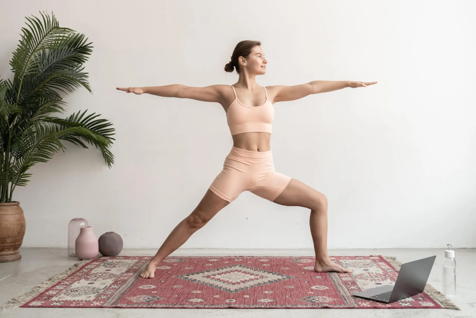 Frau in Yoga-Pose auf Matte mit Laptop, Meditation und Wellness