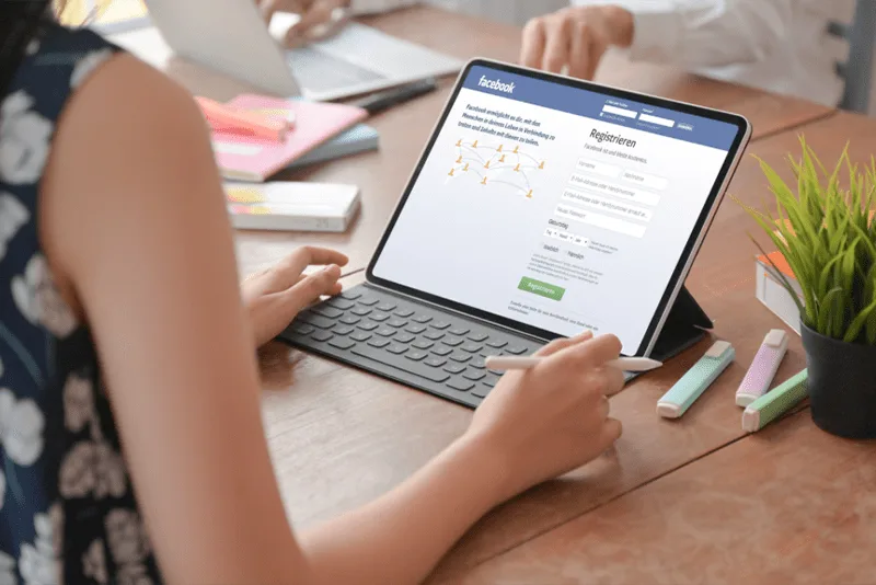 Hände an Tablet mit Facebook-Seite, Social-Media-Community-Zugang
