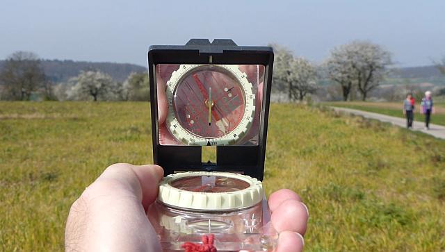 Kompass zum Peilen in Landschaft mit Person im Hintergrund