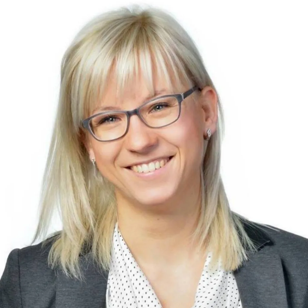 Julia Bock, Porträt einer Frau mit blondem Haar und Brille im dunklen Blazer