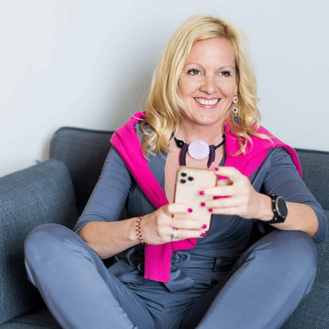 Béatrice Drach mit Smartphone und Kopfhörern auf Sofa – Kontakt