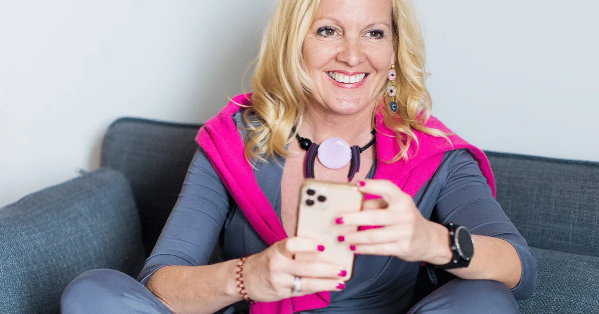 Béatrice Drach mit Smartphone und Kopfhörern auf Sofa – Portrait