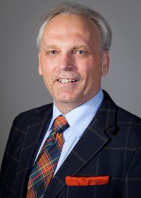 Porträt Walter Eisele Headshot, dunkler Anzug mit gestreiftem Hemd und karierter Krawatte