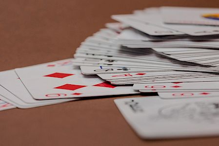 Spielkarten mit Karo-Symbolen und gestapelte Kartenstapel auf braunem Hintergrund