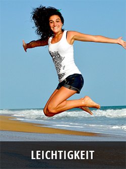 Frau springt am Strand in die Luft, Meer und blauer Himmel im Hintergrund