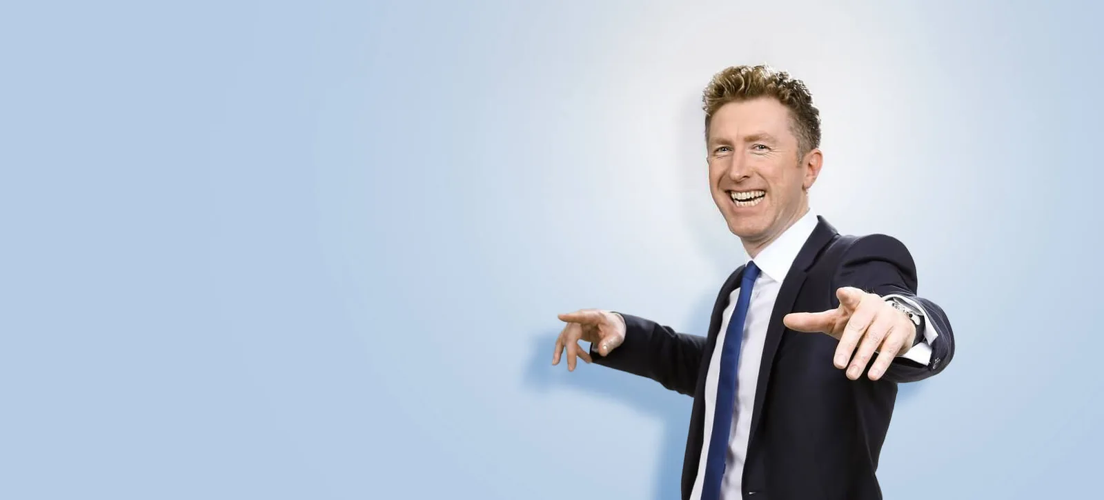 André May im Onlineshop-Banner, Geschäftsmann im dunklen Anzug mit blauer Krawatte zeigt auf die Kamera, hellblauer Hintergru