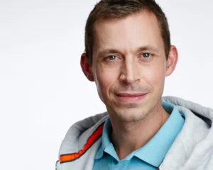 Porträt-Foto von Sebastian Glöckner, Online-Kurs Coach in hellblauem Hemd mit grauer Jacke