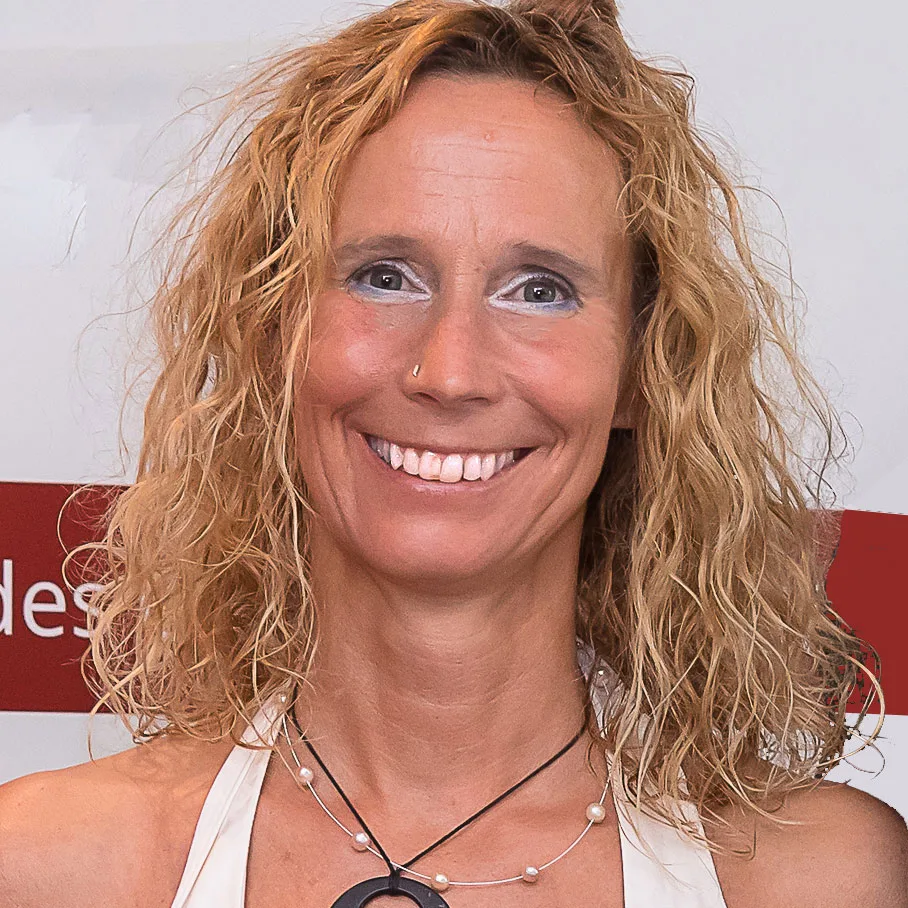 Liv Wach mit lockigem braunem Haar und Halskette lächelnd, Nahaufnahme Gesicht