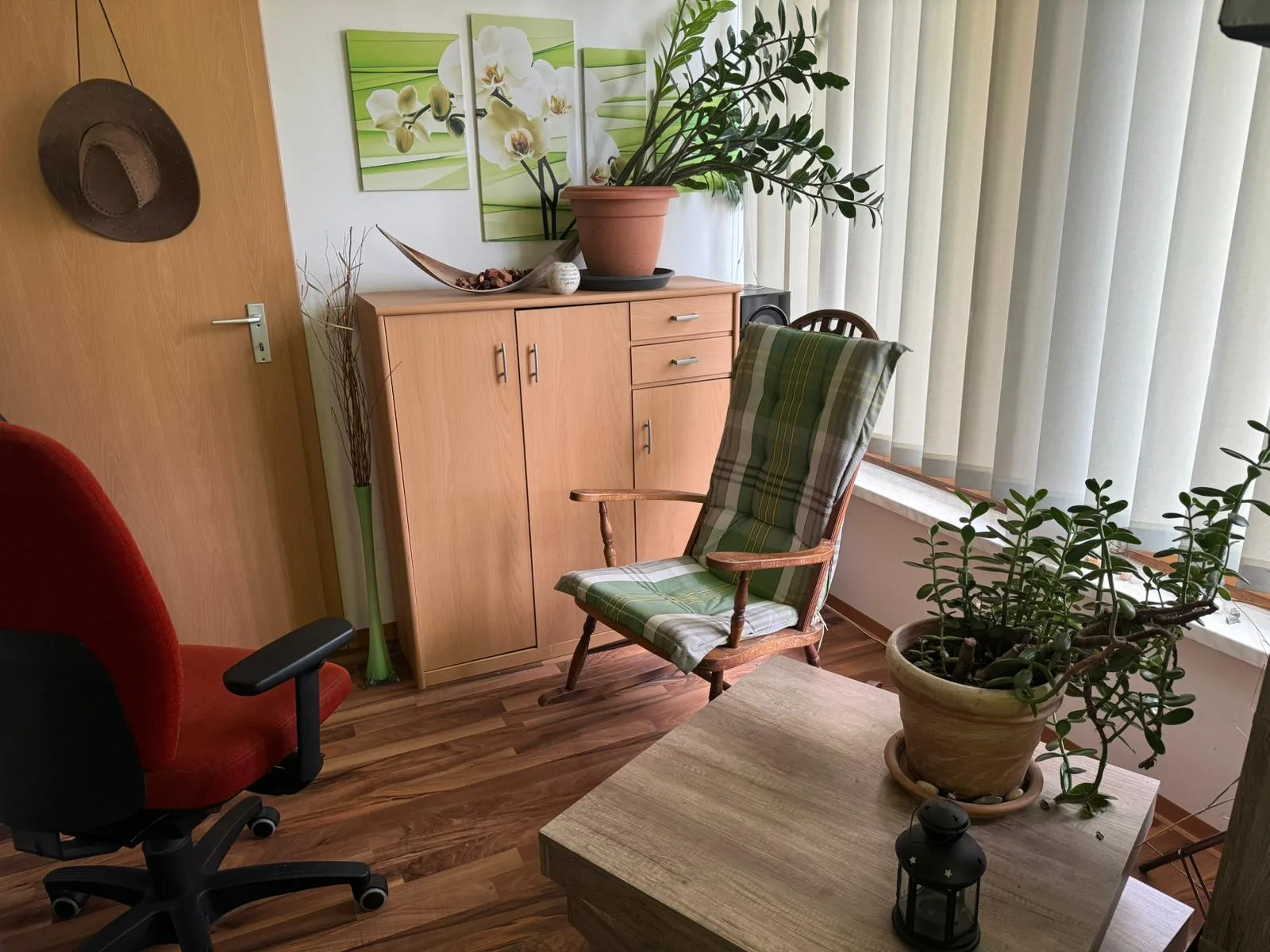 Modernes, helles Coaching-Büro mit grünen Pflanzen, rotem Stuhl und Wohnzimmer-Atmosphäre