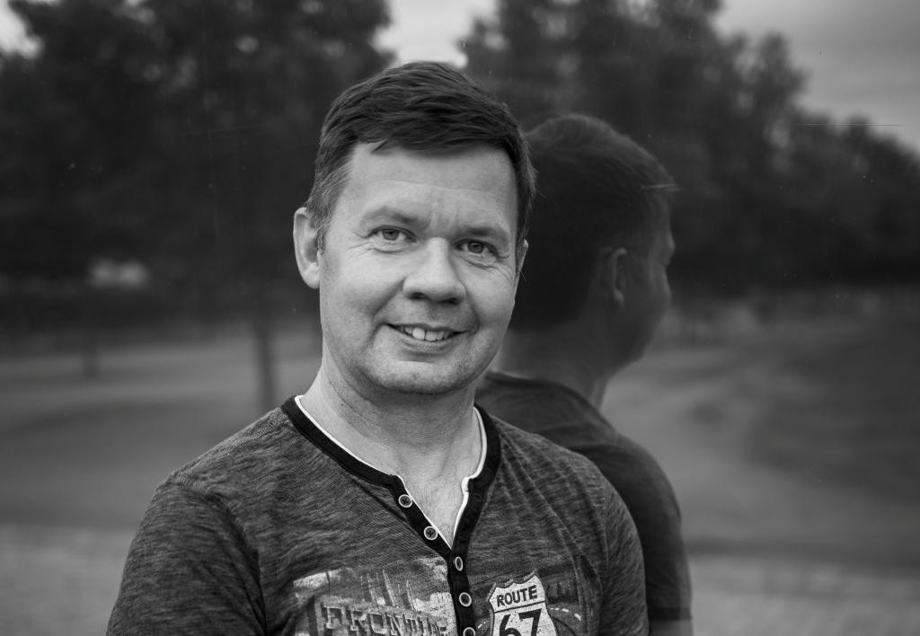 Porträt von Uwe Krämer, Coach mit freundlichem Lächeln, schwarz-weiß Fotografie