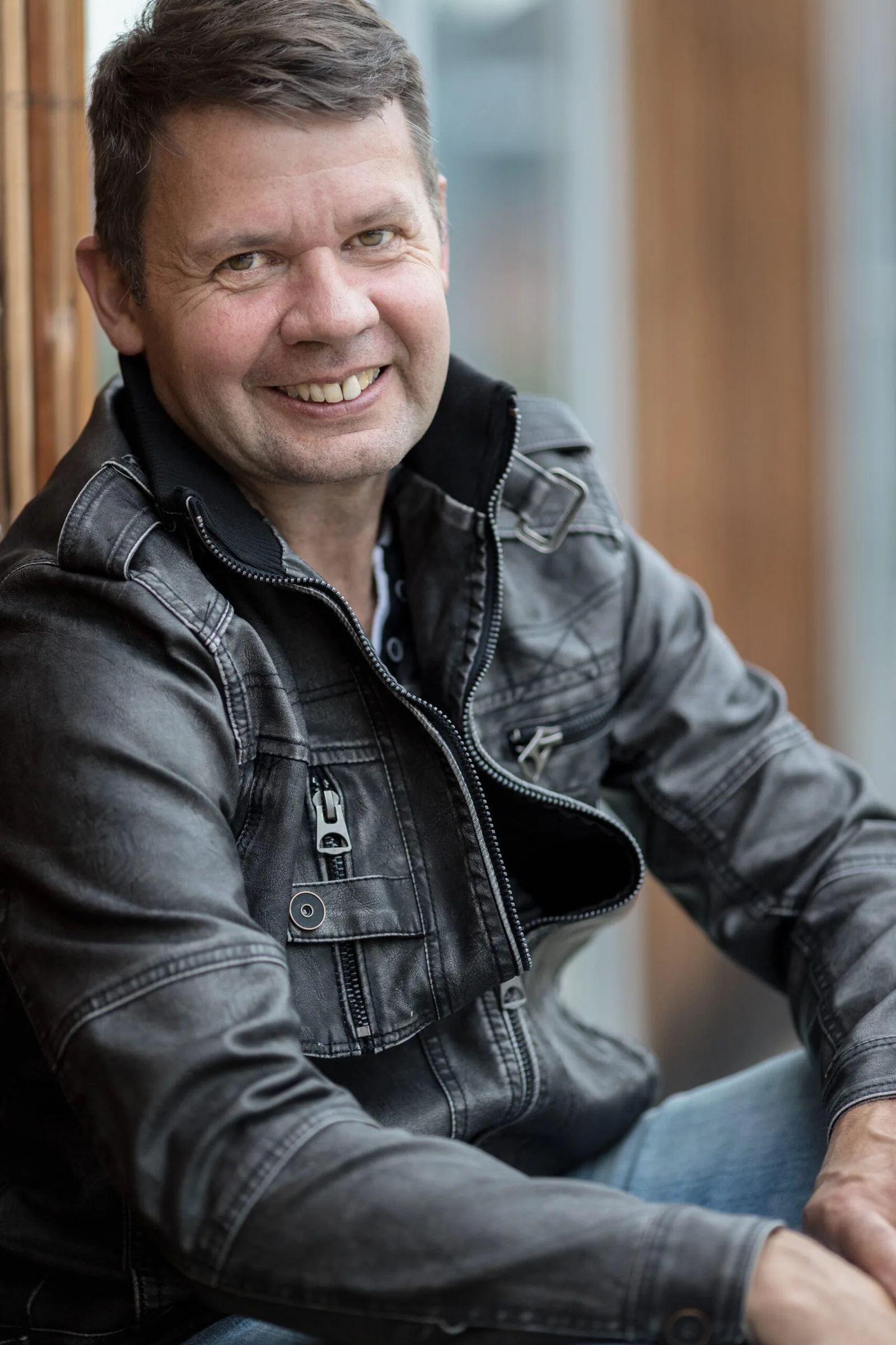 Porträt von Uwe Krämer, Coach und Mentor, lächelnd in Jeansjacke