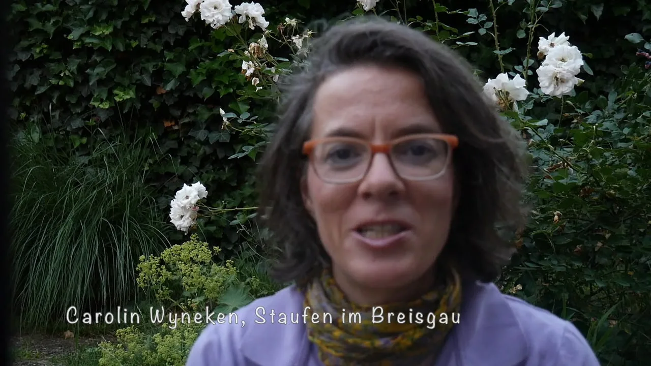 Frau mit dunklem Haar und Brille vor weißen Rosen, Text: Carolin Wyneken, Staufen im Breisgau