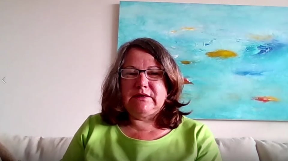 Frau mit Brille in grünem Shirt vor abstraktem Fischgemälde
