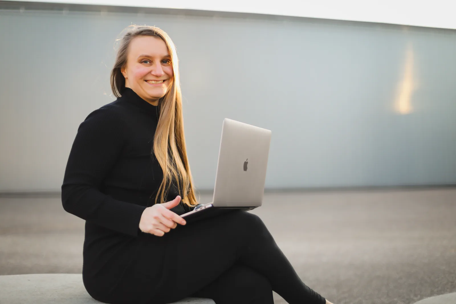 Blogtimize – Videokurs zur Blog-Optimierung von Judith Peters 1 Porträt einer lächelnden Frau mit langen braunen Haaren in schwarzem Rollkragenpullover und MacBook