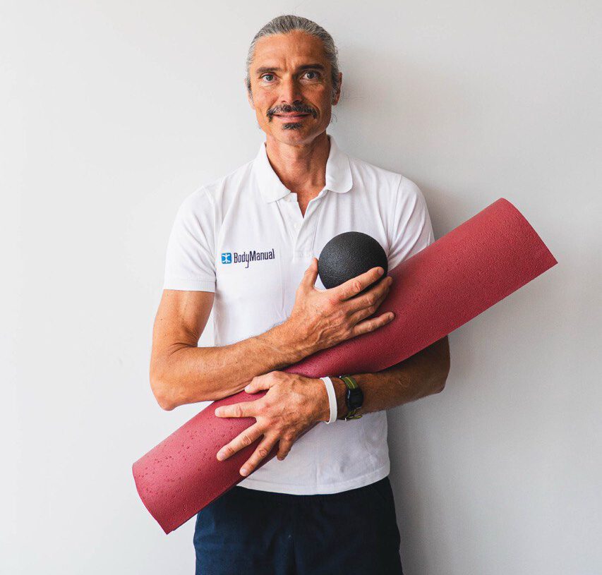 Bodymanual – Faszien-Kurs für Faszien & Beweglichkeit 2 Porträt von Quirin Waldhauser in weißem BodyManual-Poloshirt mit Trainingsmatte und Faszienball