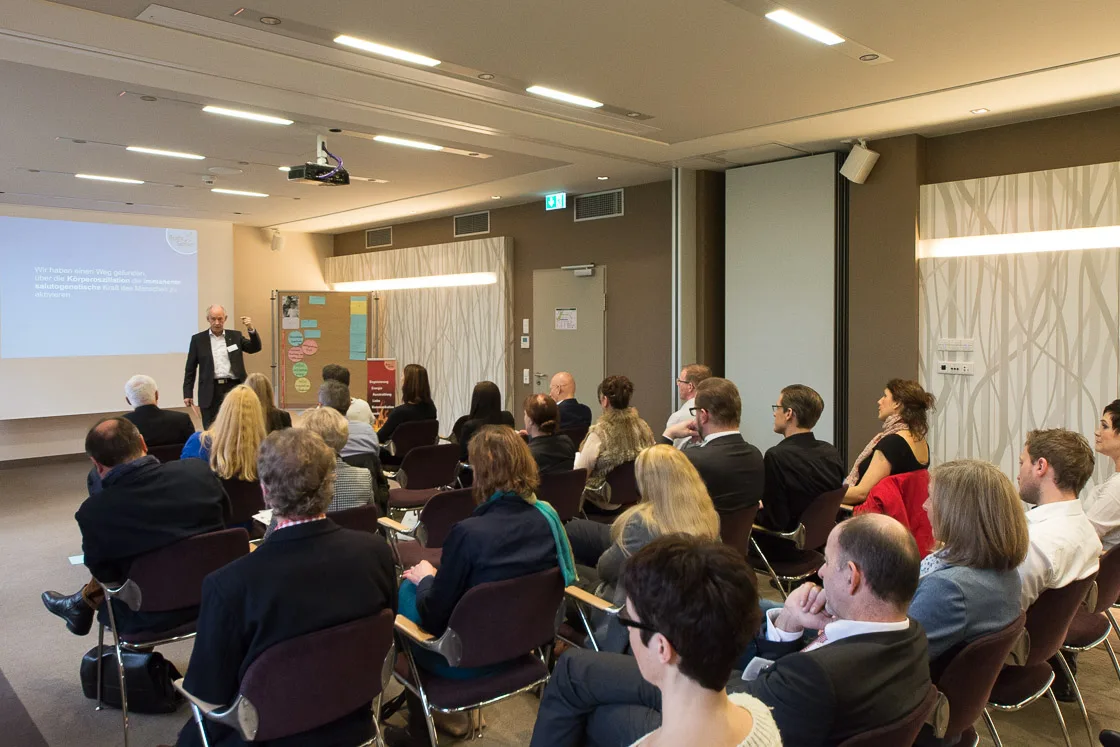 Konferenzsaal mit Publikum und Redner bei Präsentation über Gesundheitsresort in Freiburg