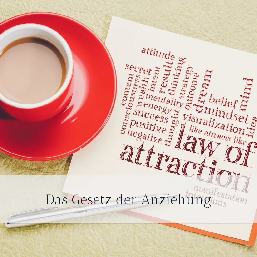 Buchmarketing Magie – Videokurs zur Autorenmarke 3 Roter Kaffeebecher neben Notizbuch mit Gesetz der Anziehung Text und Stift