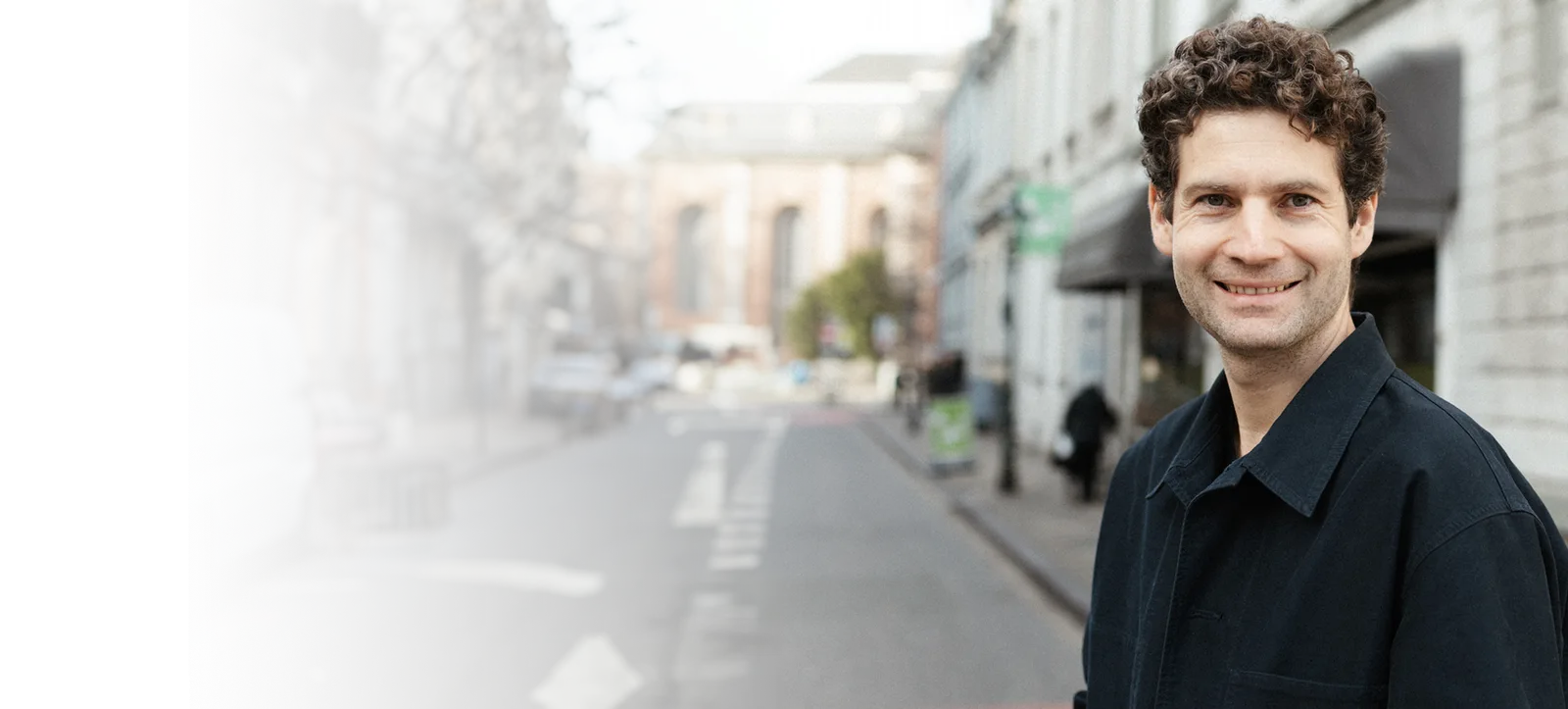 Gilles Pascher, Autor der Business-Builder Academy, lächelt in die Kamera auf einer Stadtstraße