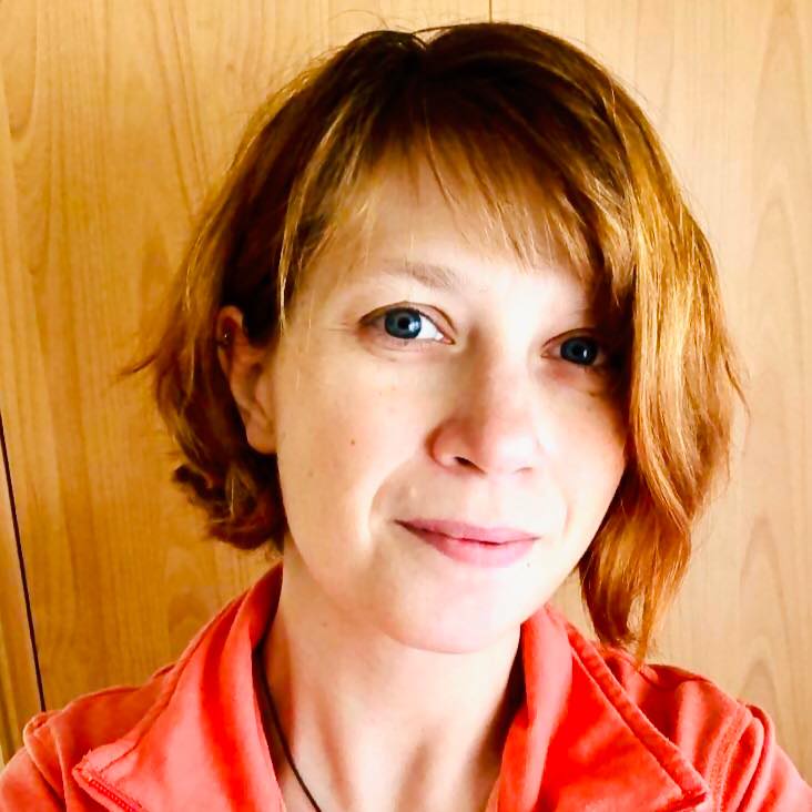 Petra Ecker Portrait mit rotem Oberteil vor Holzwand