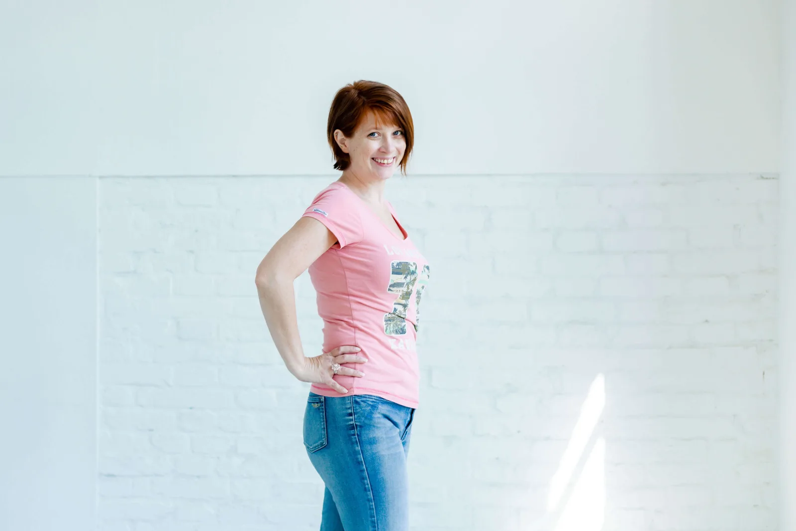 Petra Ecker in rosa T-Shirt vor weißer Backsteinwand
