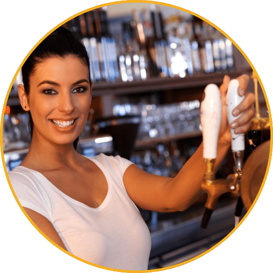 Businessplan Gastronomie/Kneipe – Vorlagenpaket mit Finanzplan 12 Barkeeperin mit langen dunklen Haaren an der Bar, serviert ein Getränk, Flaschenregal im Hintergrund