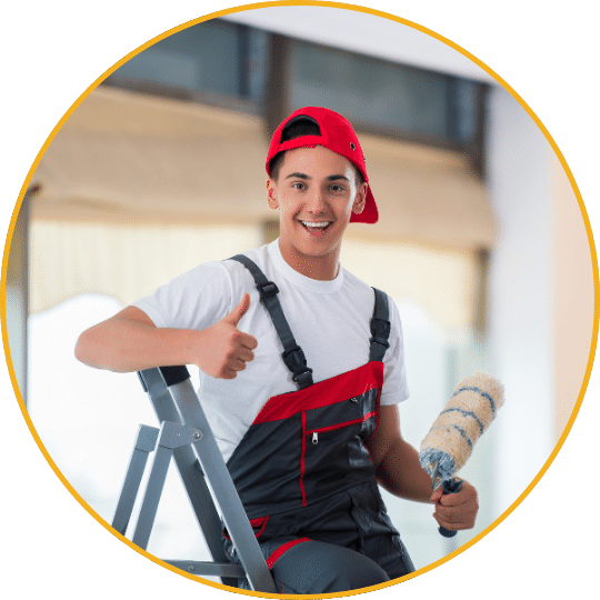 Junger Handwerker mit roter Kappe und Arbeitsoverall, Daumen hoch, Leiter und Farbrolle