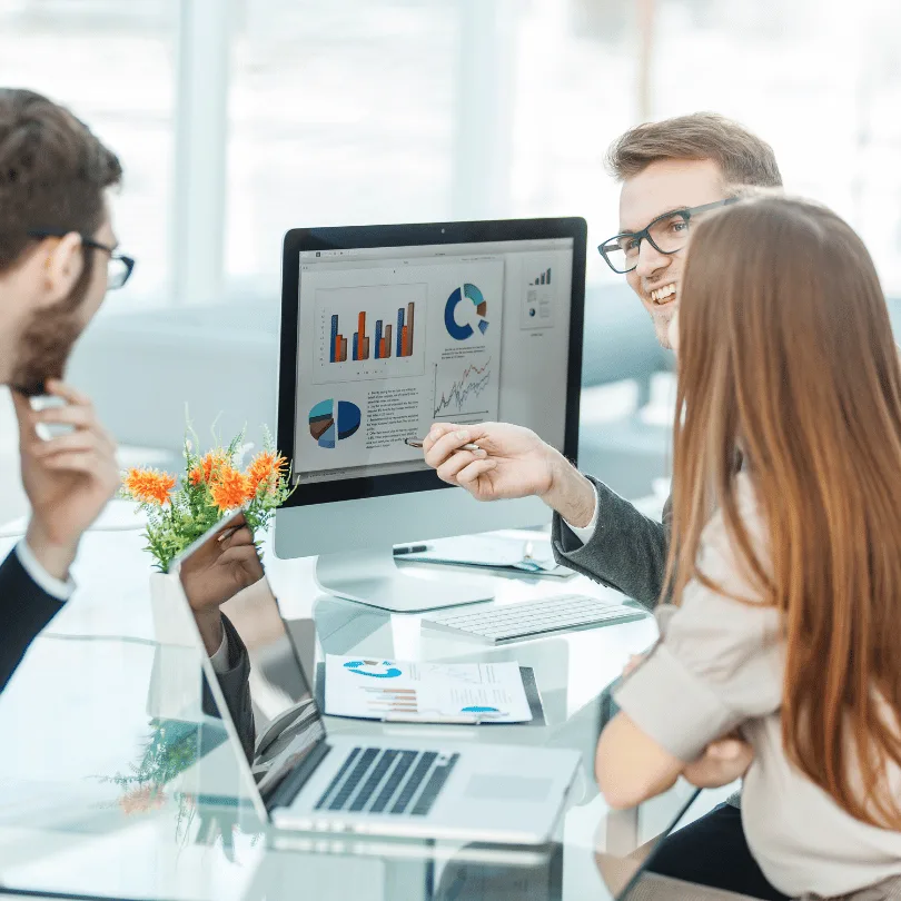 Team aus drei Personen bespricht Marketing-Analysen am Computer mit Diagrammen und Grafiken