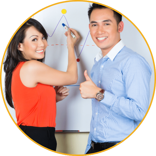 Frau in oranger Bluse und Mann in blauem Hemd zeigen auf Flipchart mit Diagramm, beide lächelnd