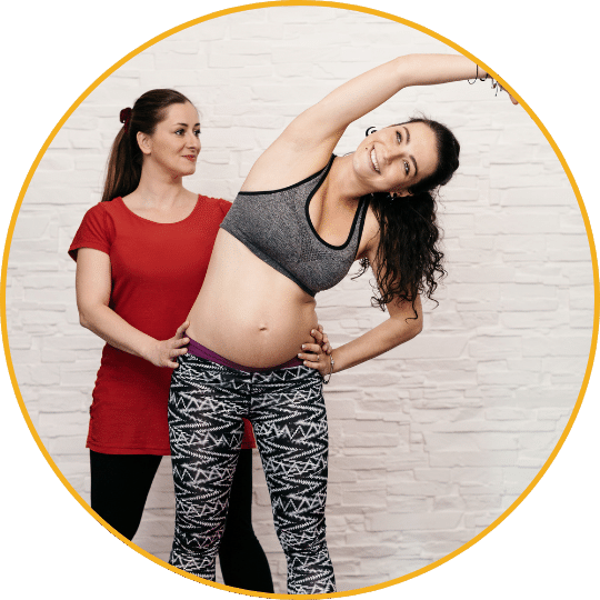 Schwangere Frau mit Personal Trainerin im roten Shirt, Bauch-Massage-Coaching im Fitnessstudio